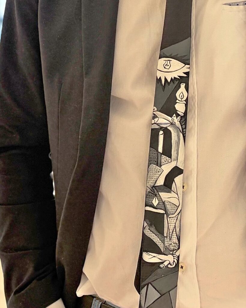 Detalle de corbata pintada a mano con escenas del Guernica de Picasso en blanco y negro